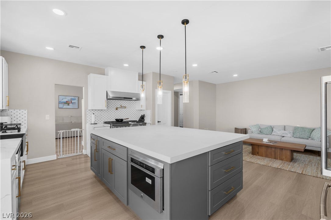 8848 Rainbow Ridge Drive, Las Vegas, NV 89117 Gleaming wood floors anchor this open-concept kitchen and living area containing a large central island.