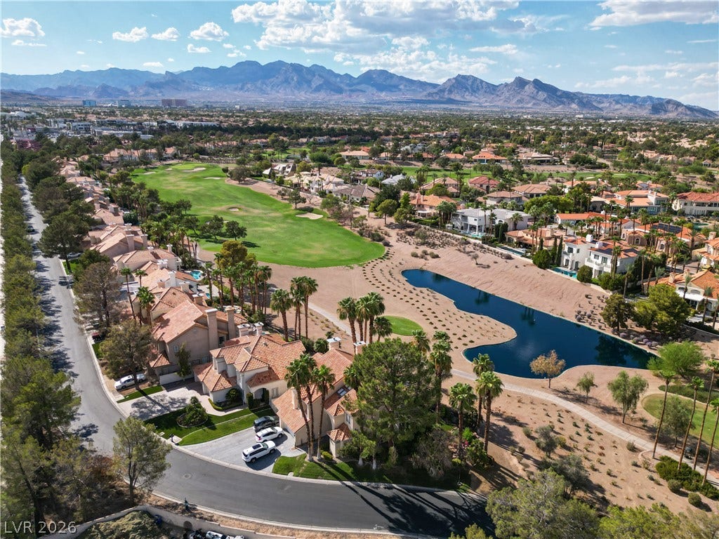 8848 Rainbow Ridge Drive, Las Vegas, NV 89117 Dramatic mountain vistas rise behind a verdant golf course and pristine desert water feature.