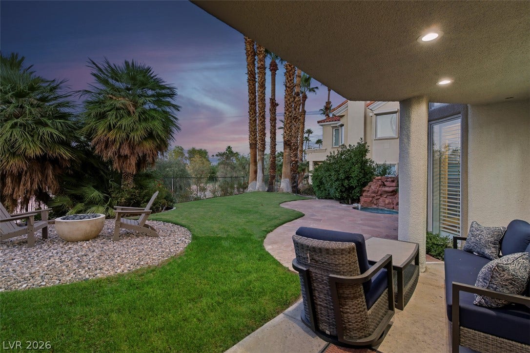 8848 Rainbow Ridge Drive, Las Vegas, NV 89117 An inviting covered patio opens directly to a lush manicured lawn framed by mature palms.