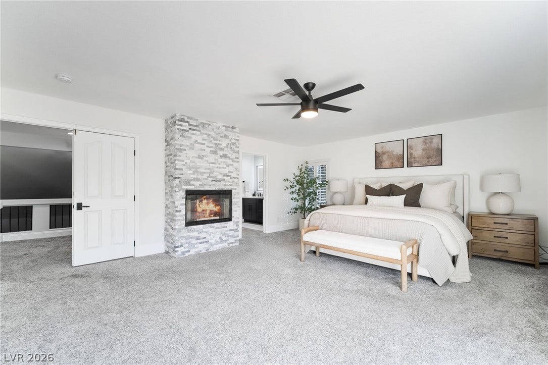 826 Rising Star Drive, Henderson, NV 89014 Plush carpeting and a stone-faced fireplace anchor this serene and spacious bedroom.