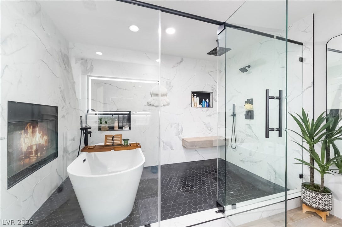 826 Rising Star Drive, Henderson, NV 89014 An elegant master bath presents a modern freestanding tub alongside a cozy fireplace.
