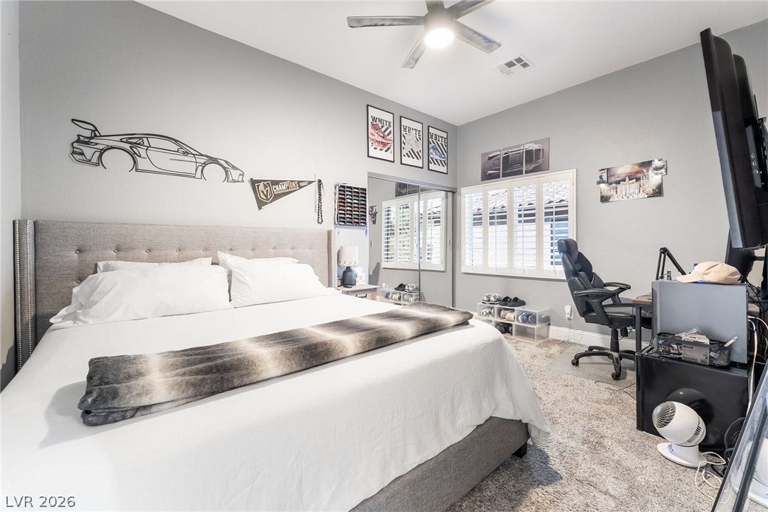 826 Rising Star Drive, Henderson, NV 89014 High ceilings and tall windows fitted with plantation shutters elevate this comfortable bedroom space.