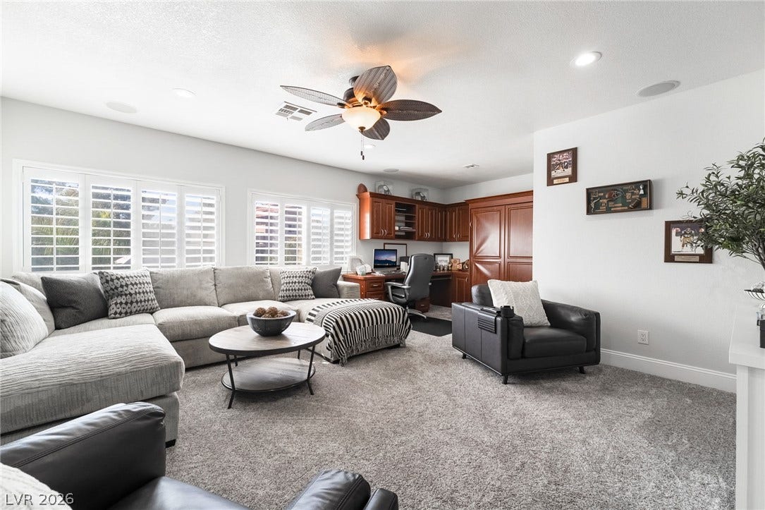 826 Rising Star Drive, Henderson, NV 89014 Generous windows with plantation shutters illuminate a spacious living area featuring built-in cabinetry and carpeting.