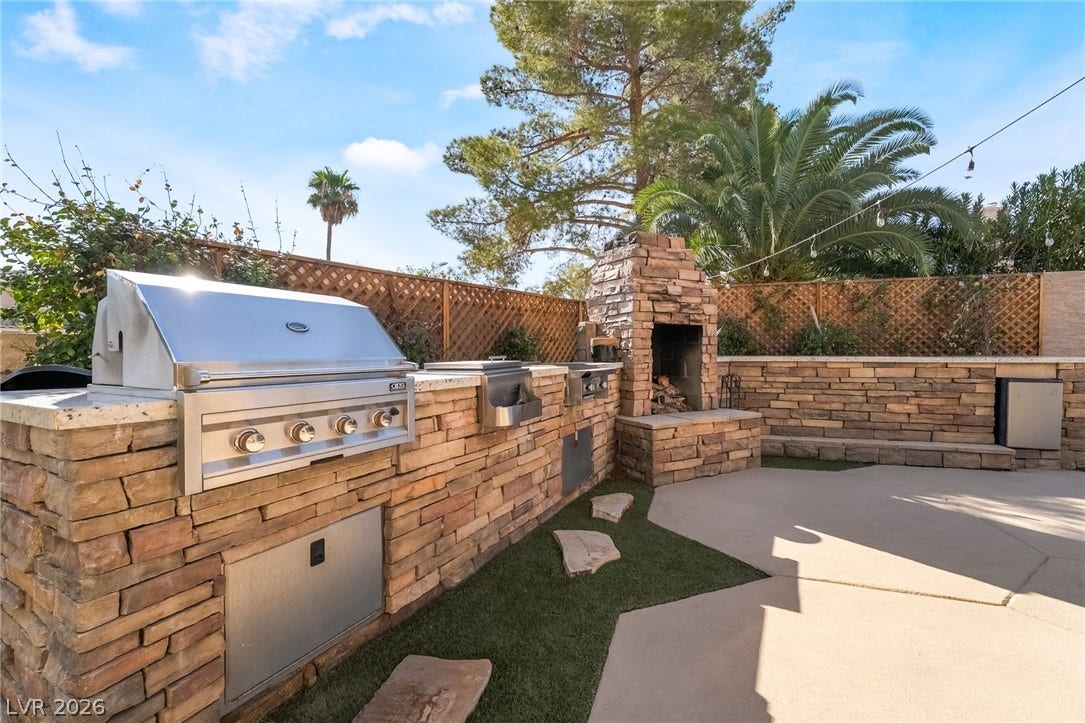 826 Rising Star Drive, Henderson, NV 89014 Stacked stone wraps this outdoor kitchen featuring a built-in barbecue grill and a brick fireplace.