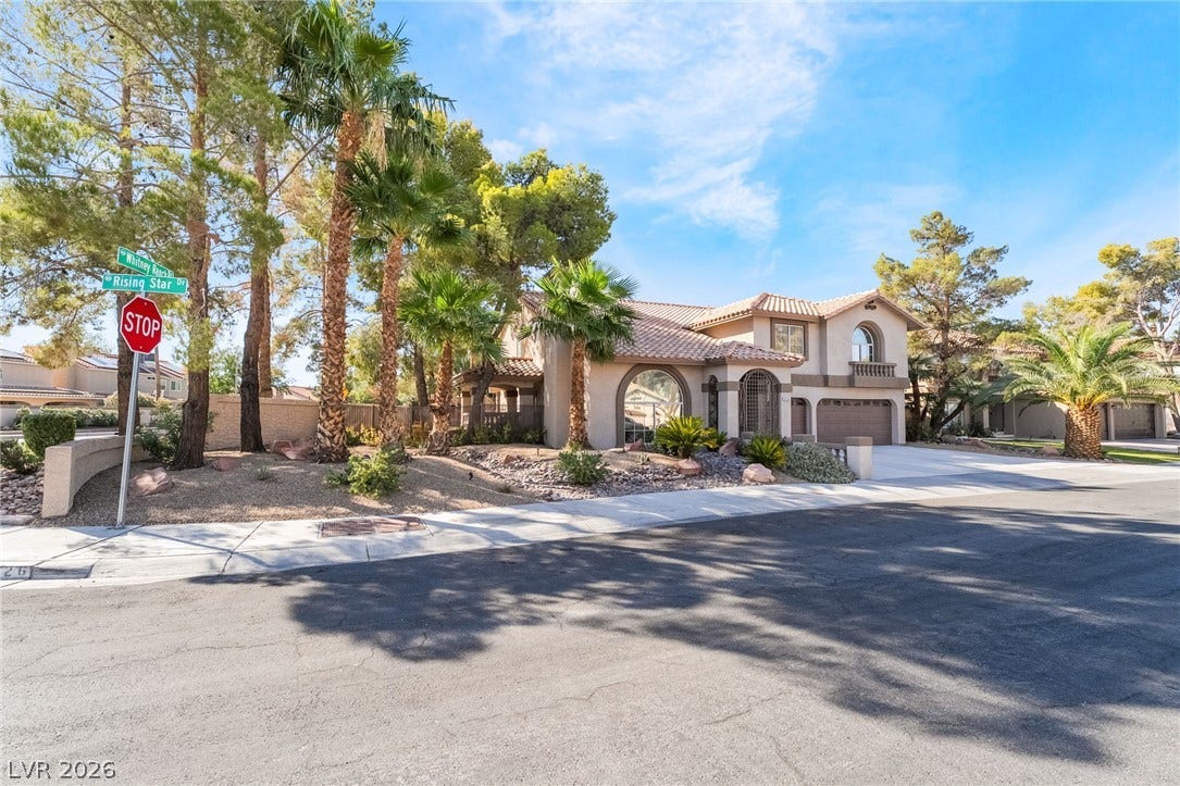 826 Rising Star Drive, Henderson, NV 89014 Mature palms frame a stucco exterior topped with Spanish tile roofing on a corner lot.