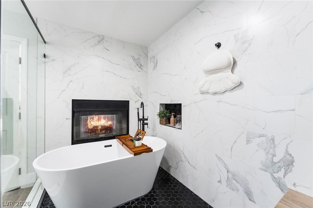 826 Rising Star Drive, Henderson, NV 89014 Marble patterned walls encase a freestanding soaking tub situated beside a glass-enclosed fireplace.