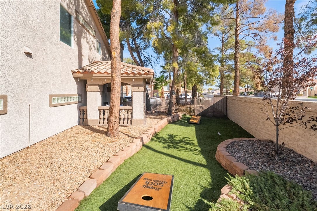 826 Rising Star Drive, Henderson, NV 89014 Mature trees shade a manicured synthetic turf lawn nestled behind a private stone boundary wall.