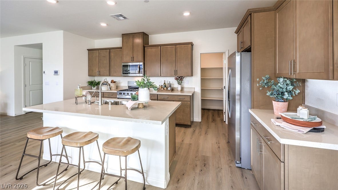 561 Ivory Peacock Ct, Henderson, NV 89011 Warm wood cabinetry and durable stone countertops anchor a highly functional open kitchen design. Photos are of a model home and are for representational purposes only.