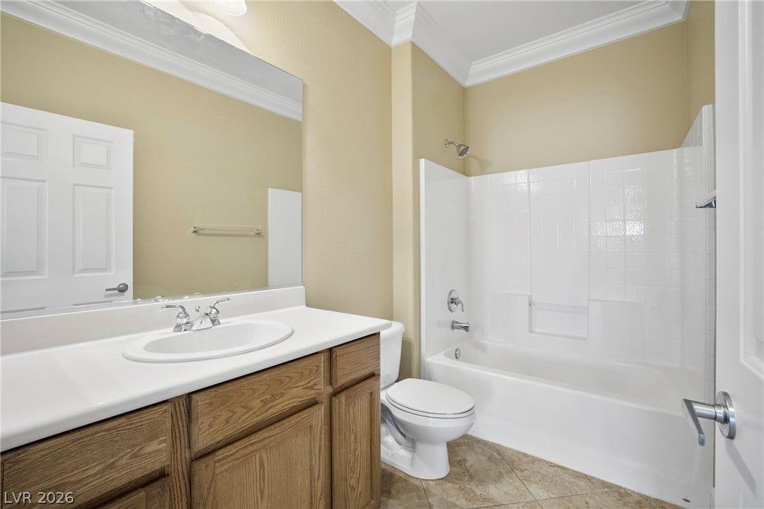 2247 Shadow Canyon Drive, Henderson, NV 89044 An elegant bathroom features classic crown molding and a clean tub and shower surround.