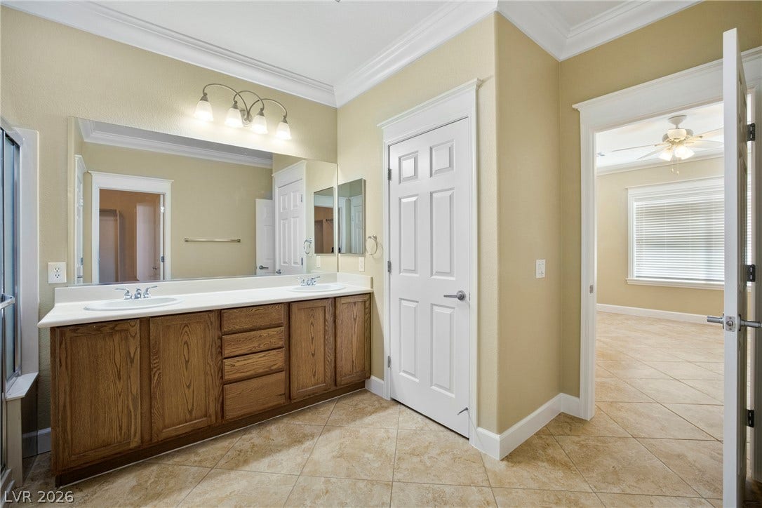 2247 Shadow Canyon Drive, Henderson, NV 89044 Elegant crown molding complements a dual-sink vanity and classic tiled flooring in this spacious bathroom.