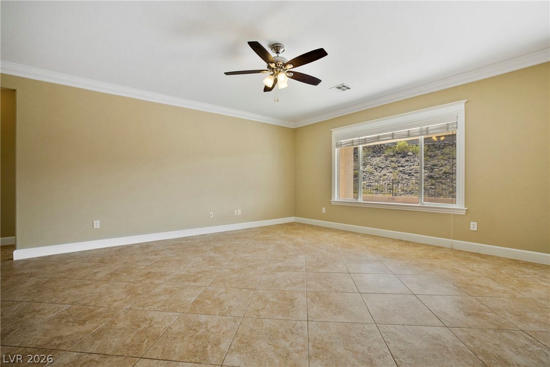 2247 Shadow Canyon Drive, Henderson, NV 89044 Tiled flooring and crown molding frame a spacious room looking out to the hillside.