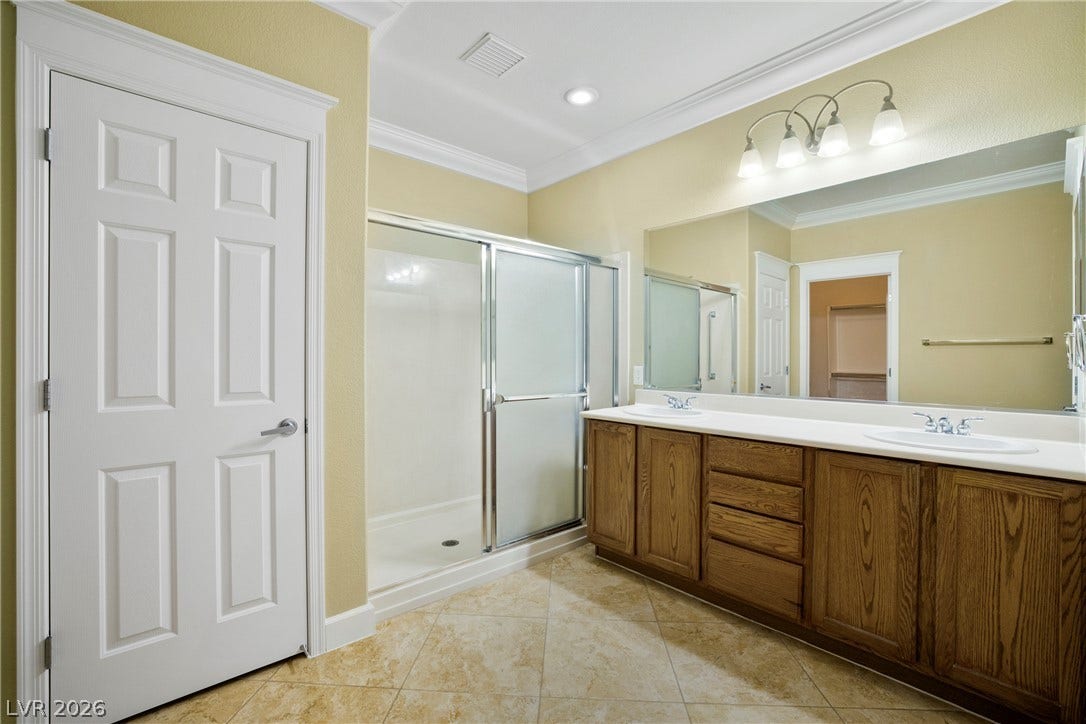 2247 Shadow Canyon Drive, Henderson, NV 89044 Timeless wood cabinetry, a dual-sink vanity, and textured tile floors anchor this bathroom.