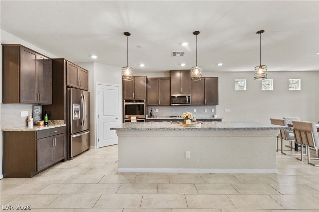 Rich wood cabinetry and expansive granite countertops define this modern, open-concept kitchen space.