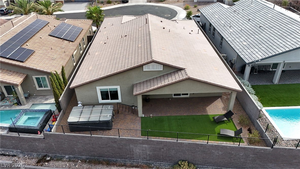 An aerial perspective showcases a tile roof and a covered patio area in the backyard.
