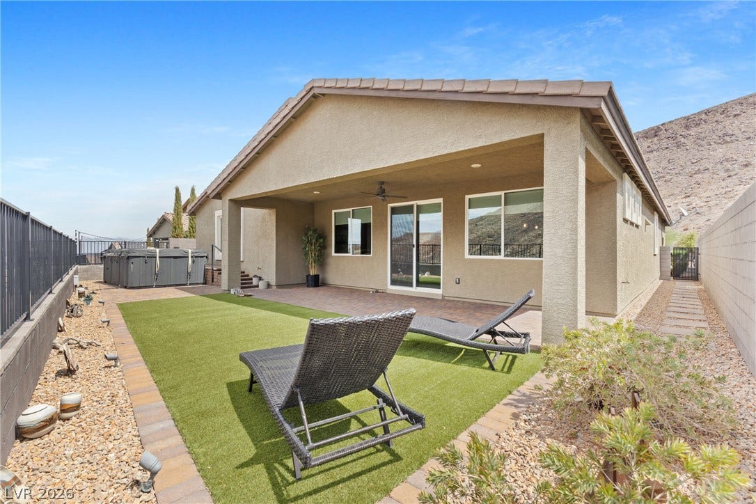 An inviting covered patio opens to a manicured lawn area beneath desert mountain views.
