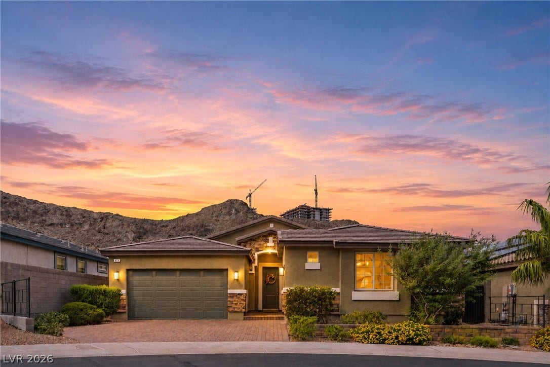 Dramatic mountain backdrops frame this modern single-story residence with a paved driveway and tiled roof.