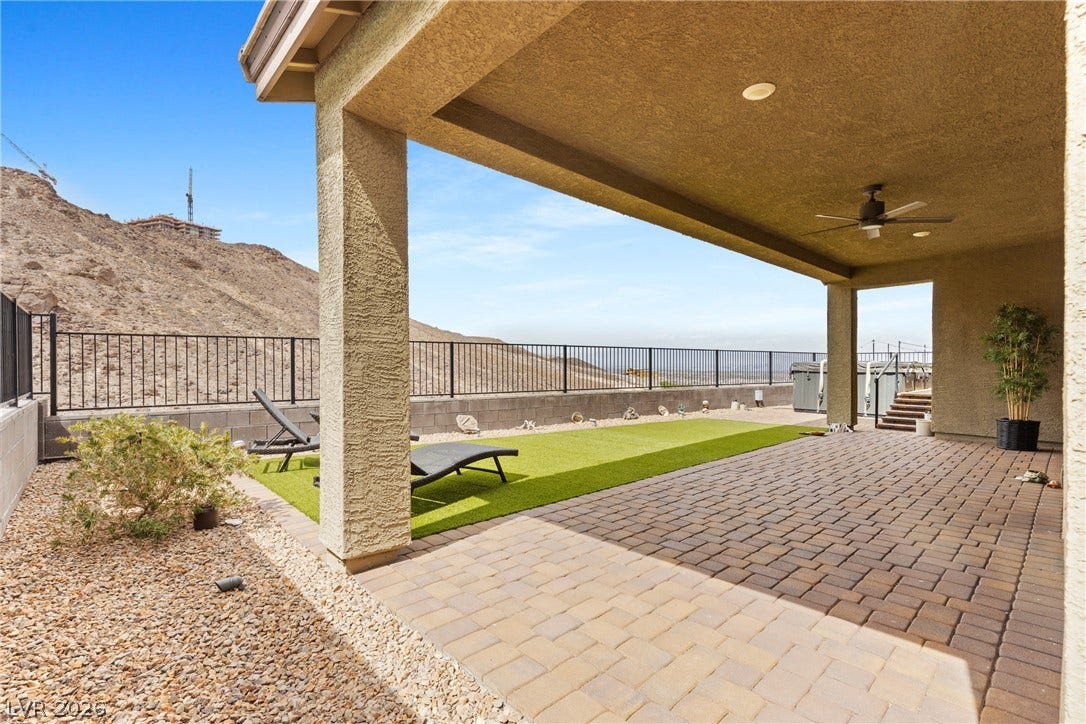 An inviting covered patio features extensive brick pavers and frames scenic desert mountain views.