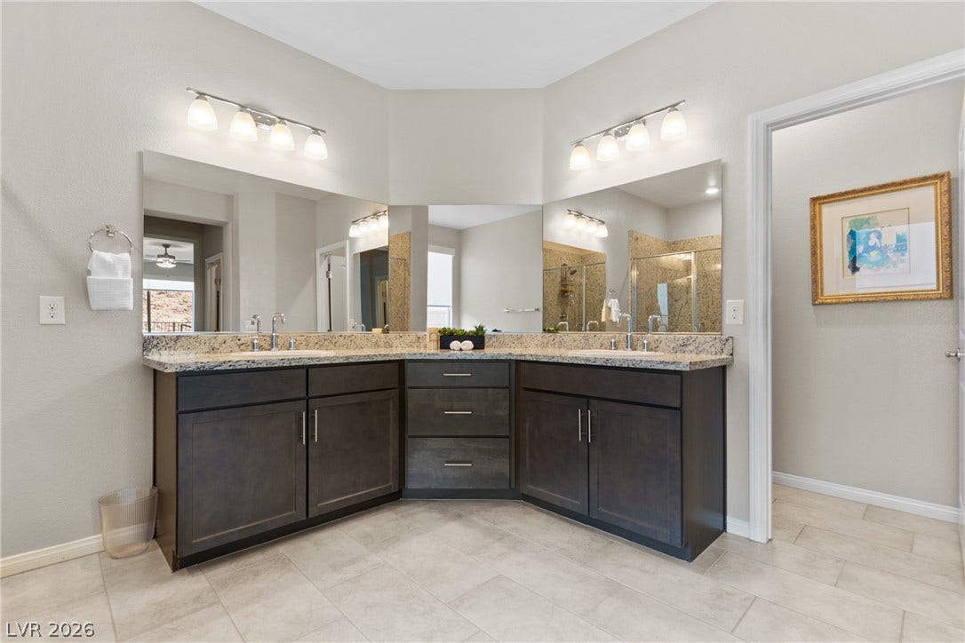 A corner vanity with stone counters anchors this spacious, tile-floored bathroom.