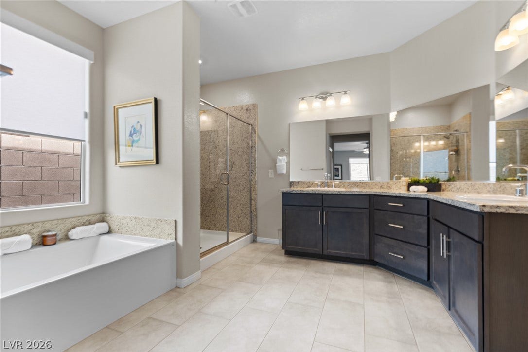 An angled double vanity is flanked by a soaking tub and a walk-in shower.