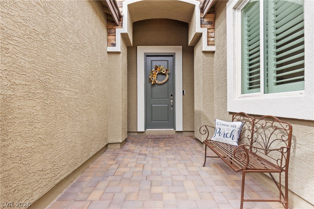 An inviting recessed entryway features patterned stone paving and a textured stucco exterior.