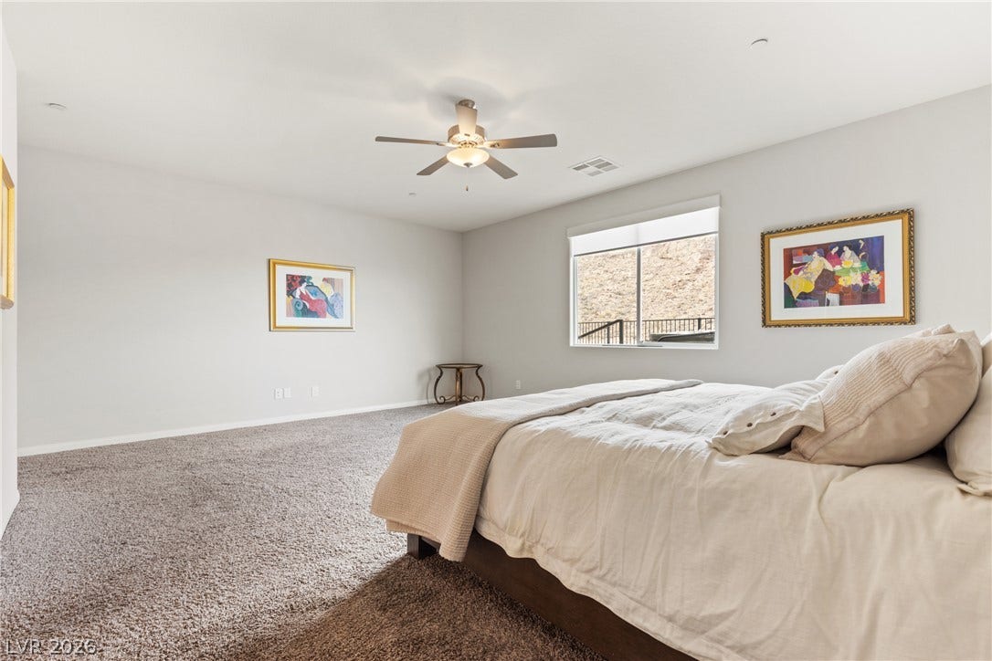 A spacious bedroom features plush carpeting and a large window looking out to the yard.