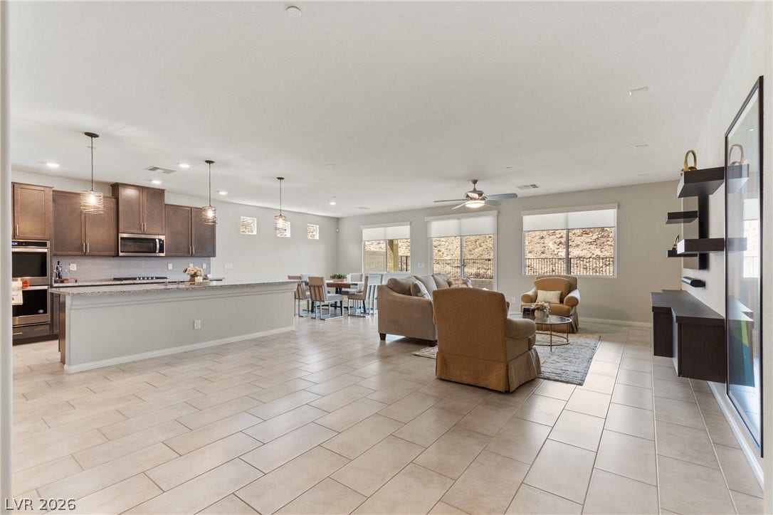 An open-concept living area flows seamlessly into the kitchen over neutral tile flooring.