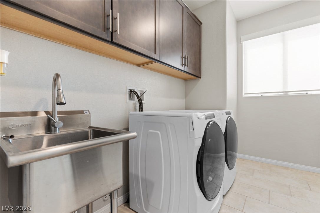 Functional workspace design highlights this neat laundry area complete with tile flooring and cabinetry.