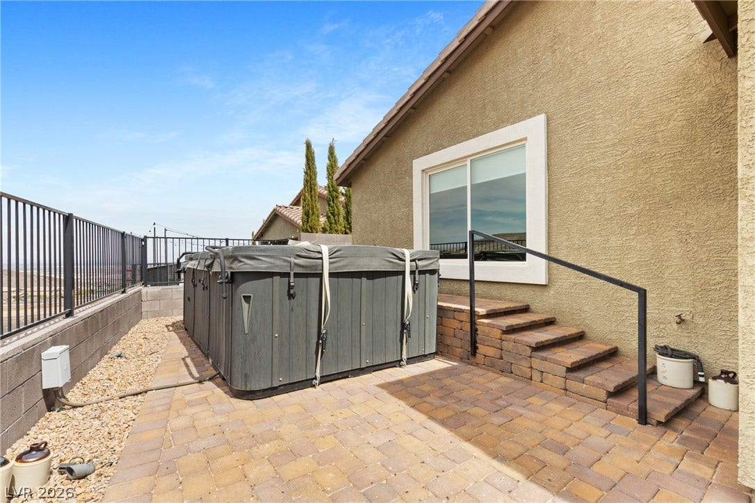 An inviting backyard patio features paving stones, elevated stucco siding, and a private hot tub.