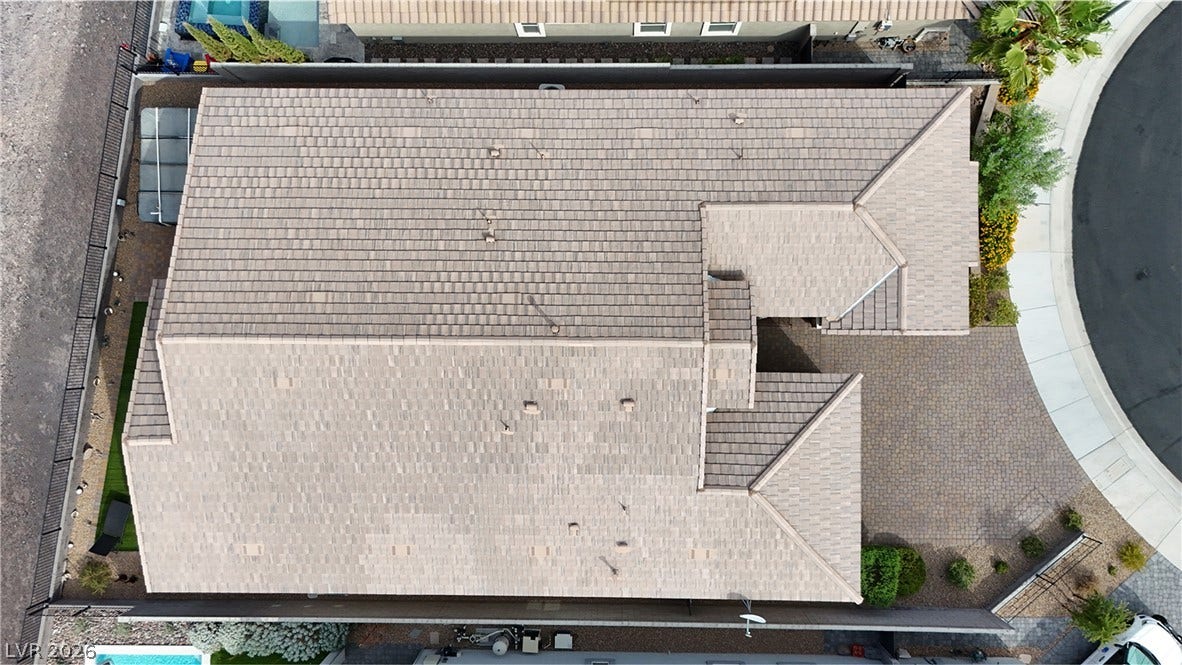 A high-angle aerial view highlights the structured roofline and pristine paver driveway.