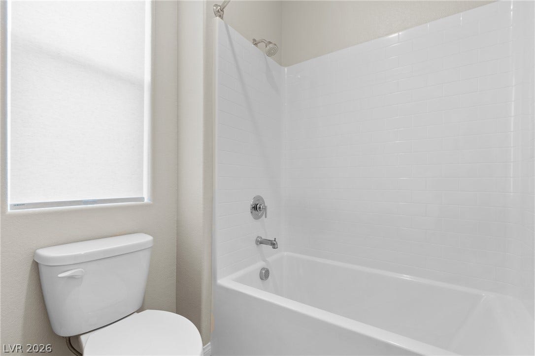 Clean lines and classic tiling define this functional bathroom space featuring a built-in tub.