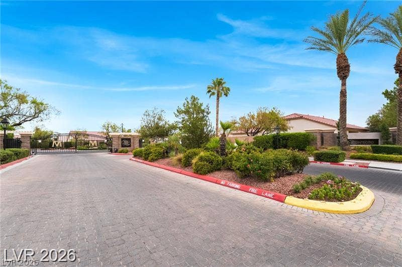 10605 Bardilino Street, Las Vegas, NV 89141 A secure gated entrance leads along a paved driveway bordered by manicured desert landscaping.