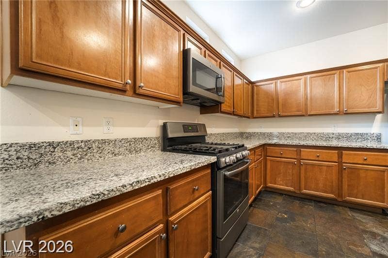 10605 Bardilino Street, Las Vegas, NV 89141 Rich wood cabinetry pairs with durable stone counters and natural slate flooring in this kitchen.