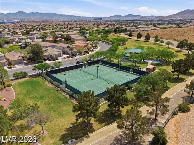 10605 Bardilino Street, Las Vegas, NV 89141 Fenced tennis courts stand adjacent to a green park with mountain silhouettes on the horizon.