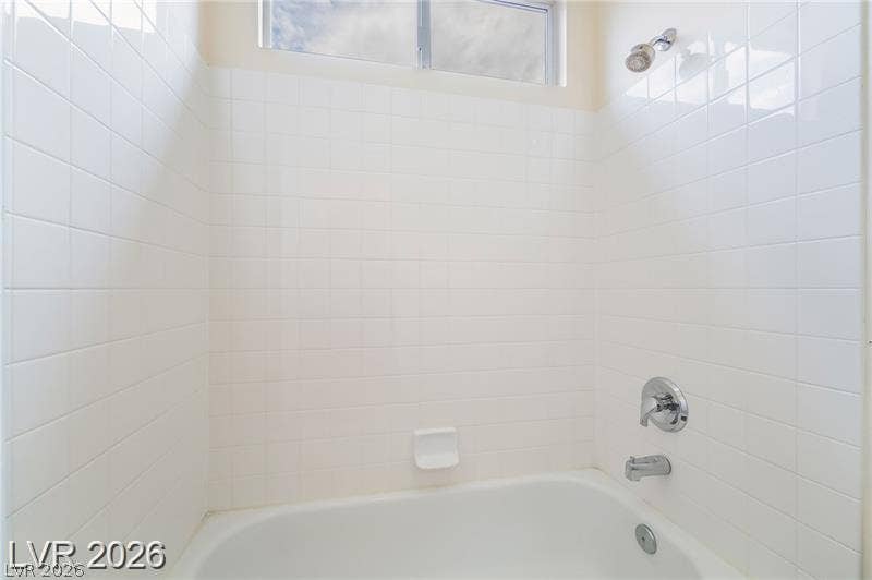 10605 Bardilino Street, Las Vegas, NV 89141 White tiled walls surround a classic tub and shower combination under a high clerestory window.