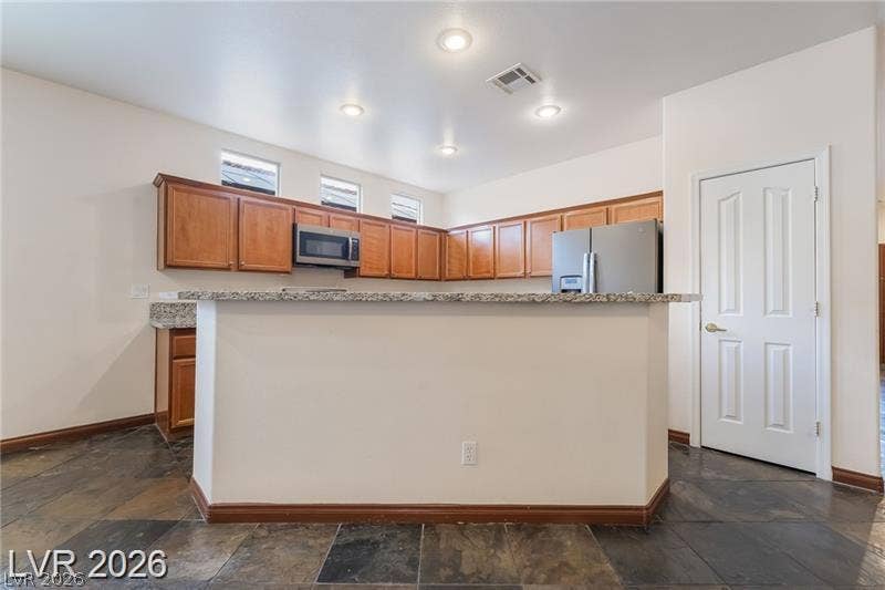 10605 Bardilino Street, Las Vegas, NV 89141 Rich wood cabinetry and stone countertops anchor this functional kitchen area featuring durable tile flooring.