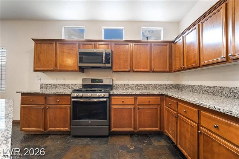 10605 Bardilino Street, Las Vegas, NV 89141 Rich wood cabinetry surrounds durable stone countertops over a dark slate floor.