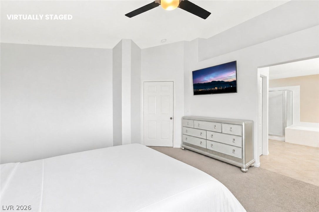 1874 Mesquite Canyon Drive, Henderson, NV 89012 A spacious bedroom featuring neutral carpeting, high ceilings, and an adjoining private bathroom.