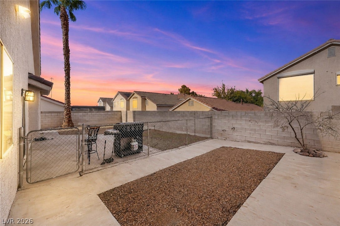 1874 Mesquite Canyon Drive, Henderson, NV 89012 A concrete patio and gravel area sit enclosed by block wall fencing under twilight skies.