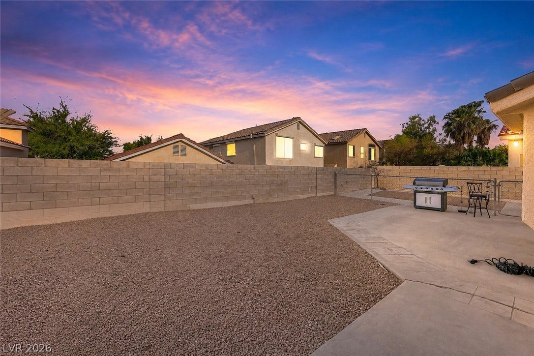 1874 Mesquite Canyon Drive, Henderson, NV 89012 An enclosed backyard features gravel landscaping, a concrete patio area, and high block fencing.