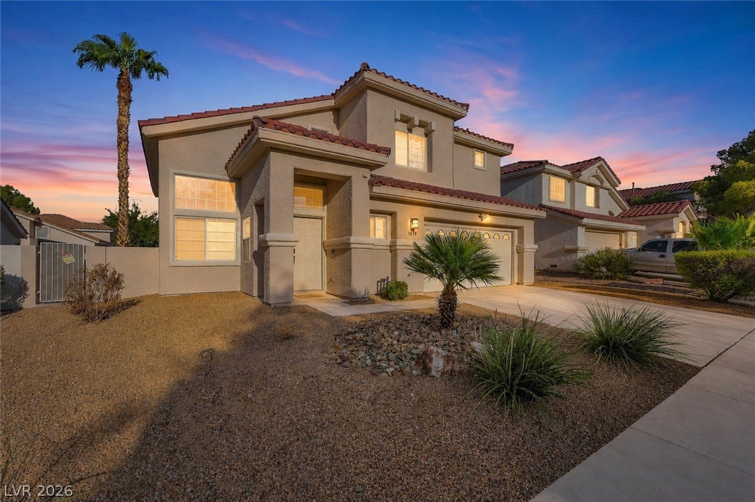 1874 Mesquite Canyon Drive, Henderson, NV 89012 Warm evening light illuminates the stucco exterior and tiled roofline of this multi-level home.