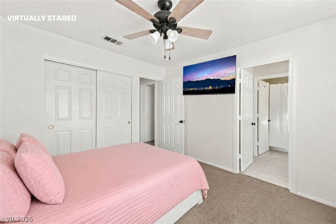 1874 Mesquite Canyon Drive, Henderson, NV 89012 Soft carpeting underfoot provides cozy comfort in this bedroom with an adjacent ensuite bathroom.