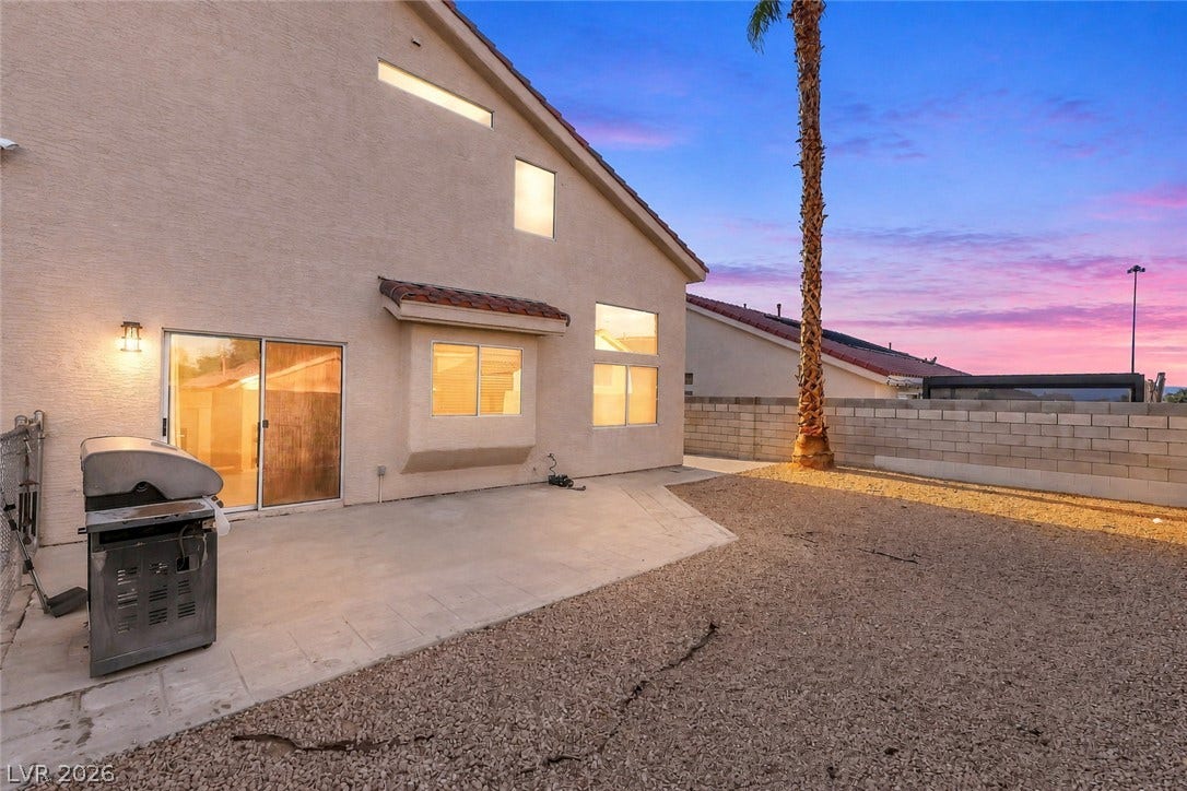 1874 Mesquite Canyon Drive, Henderson, NV 89012 A spacious concrete patio overlooks the low-maintenance desert yard under a vibrant sunset sky.