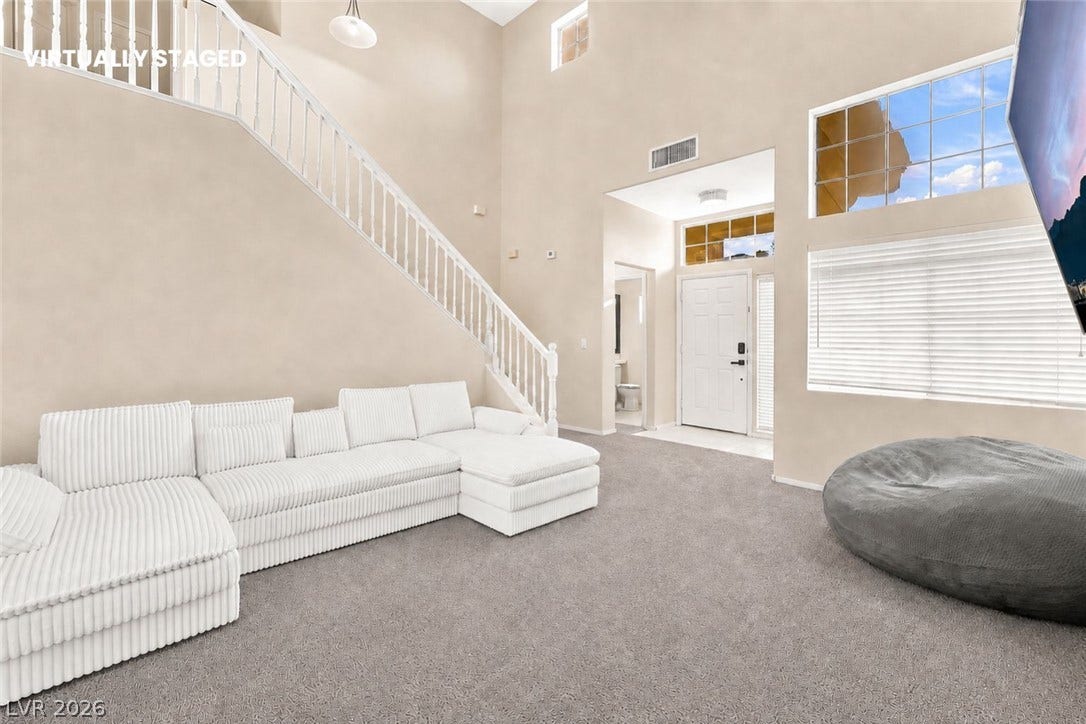 1874 Mesquite Canyon Drive, Henderson, NV 89012 Soaring ceilings and tall windows illuminate a welcoming entry and carpeted living space.