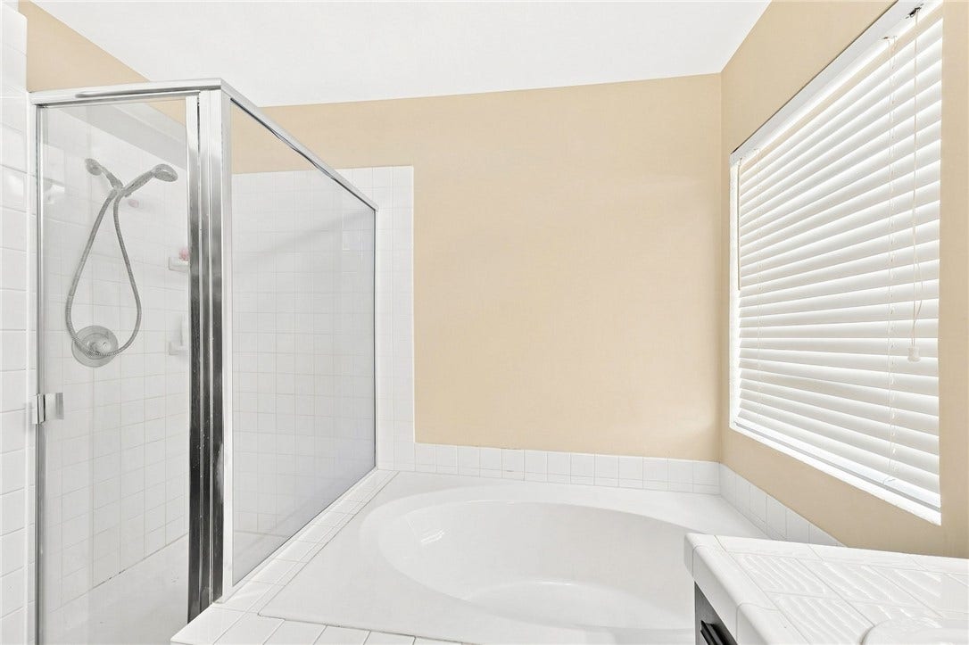 1874 Mesquite Canyon Drive, Henderson, NV 89012 A spacious soaking tub sits adjacent to a glass-enclosed walk-in shower under clean, simple lines.