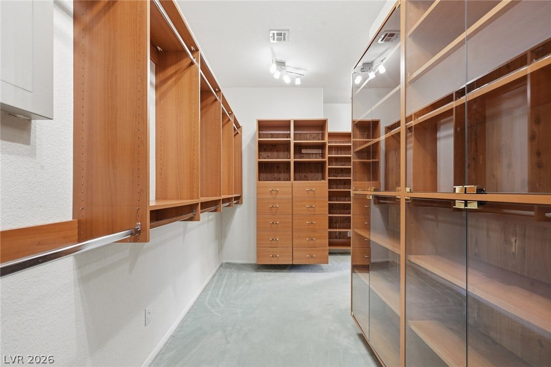 2212 Chatsworth Court, Henderson, NV 89074 Ample custom cabinetry and glass-fronted storage create an organized walk-in closet.
