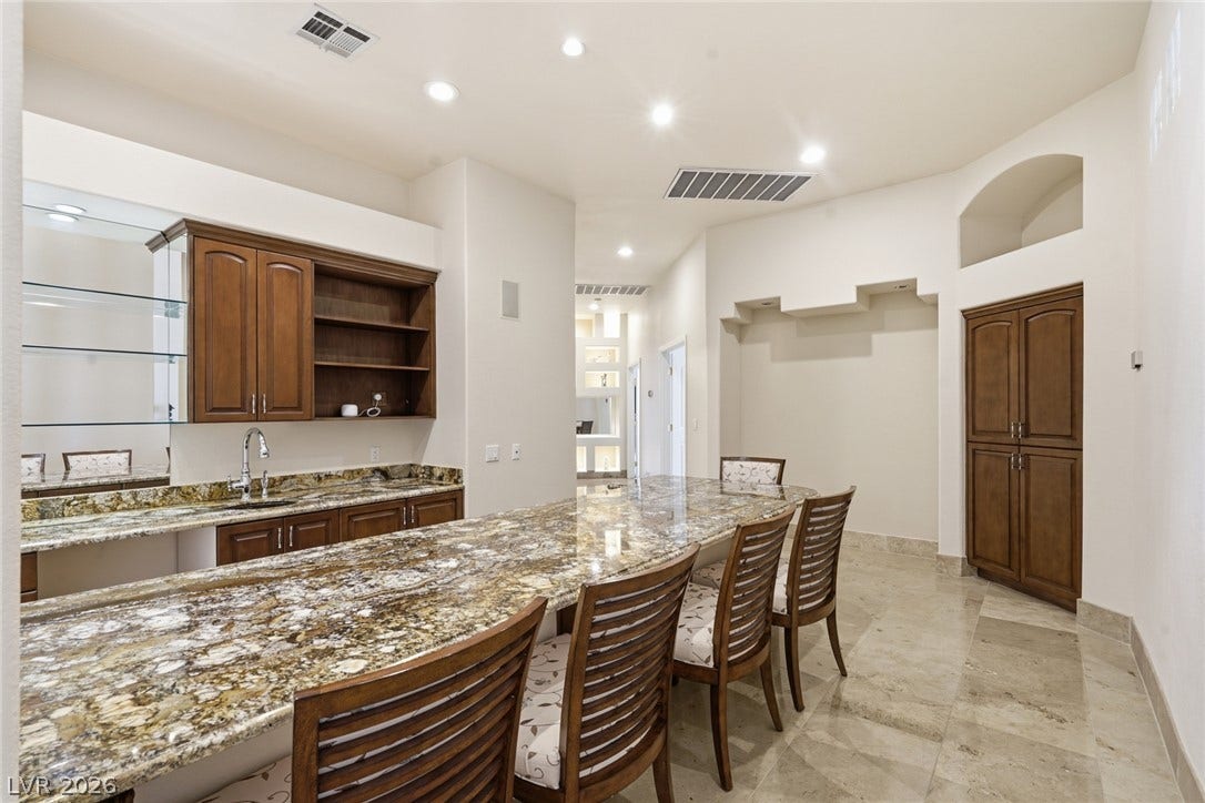 2212 Chatsworth Court, Henderson, NV 89074 A well-appointed wet bar area, featuring a long granite counter and ample cabinetry, offers an ideal spot for entertaining.