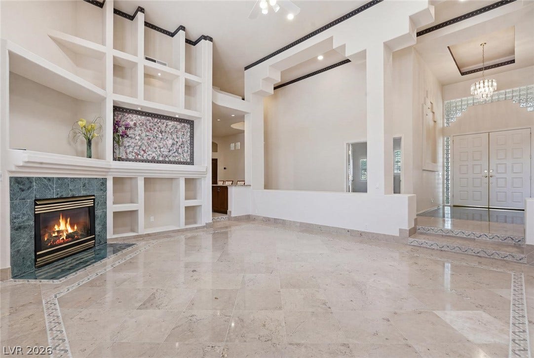 2212 Chatsworth Court, Henderson, NV 89074 A spacious living area featuring a fireplace, built-in shelving, and polished stone flooring.