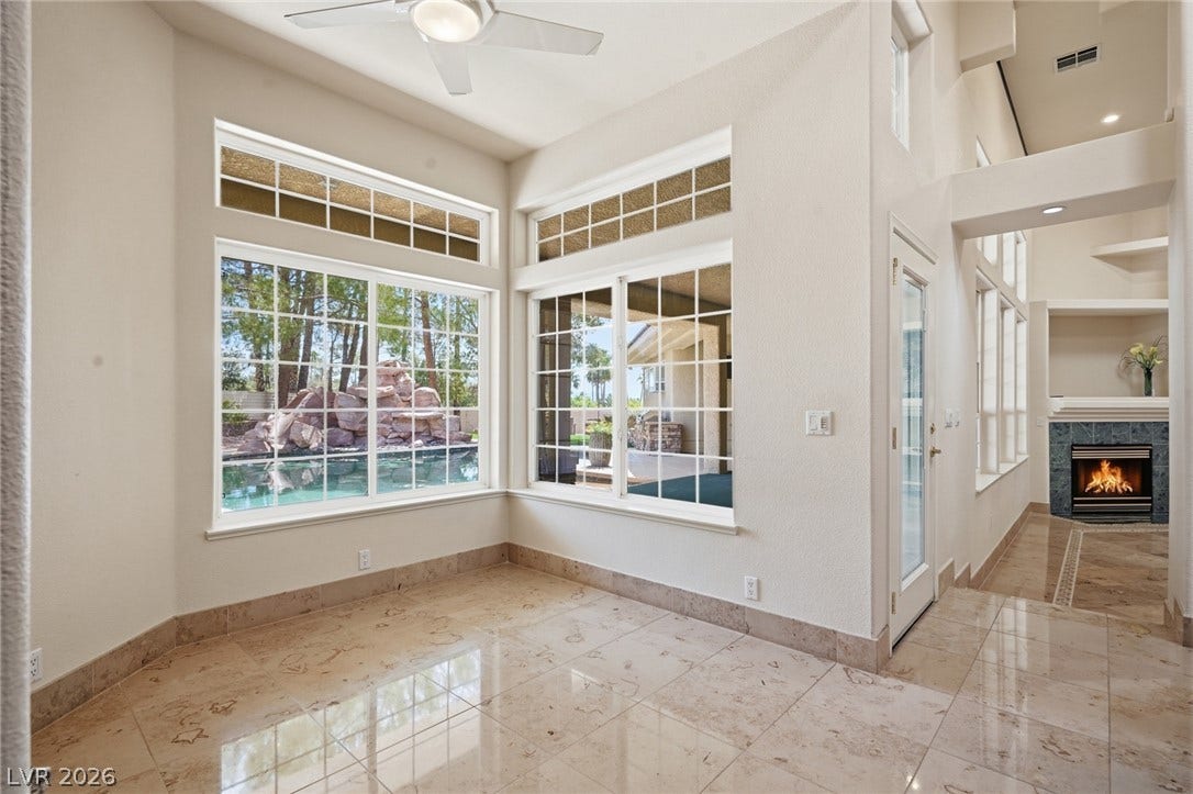 2212 Chatsworth Court, Henderson, NV 89074 A well-lit room offers pool views, high ceilings, and a corner fireplace for cozy gatherings.