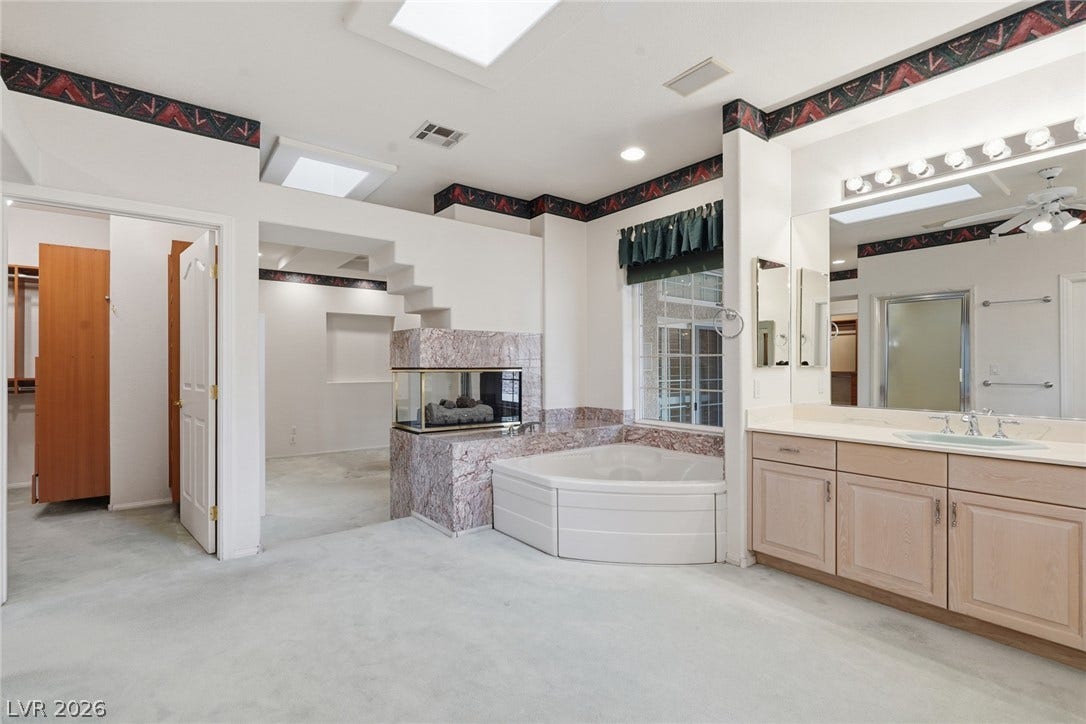 2212 Chatsworth Court, Henderson, NV 89074 Relax in this luxurious primary bathroom, featuring a corner tub and a stunning two-sided fireplace.