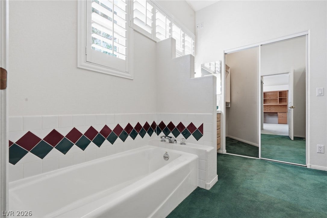 2212 Chatsworth Court, Henderson, NV 89074 A deep soaking tub awaits in this bath, featuring playful tile accents and practical privacy shutters.